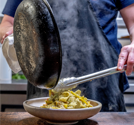 Chef plating fresh pasta from a hot pan at Rusted Rake Brewing