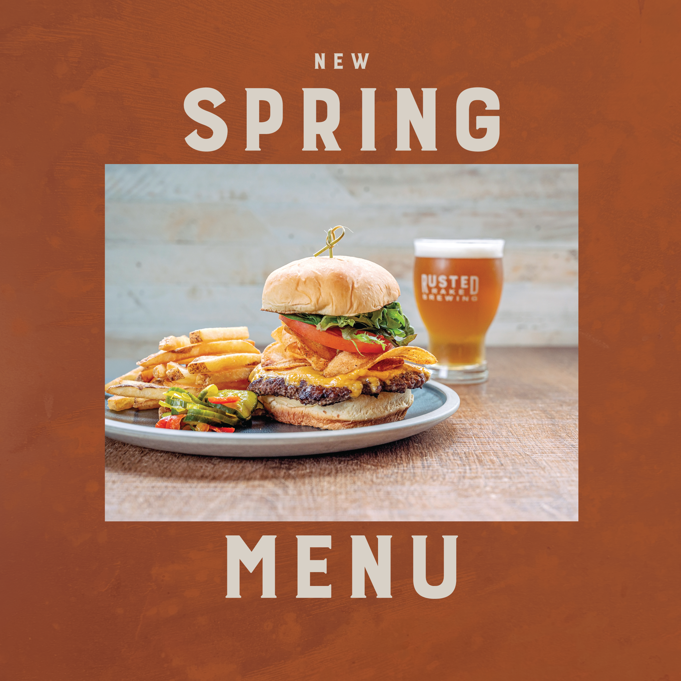 Rusted Rake Brewing spring menu cover featuring a cheeseburger with fries and a pint of beer on a rustic table against a warm burnt-orange textured background with bold cream lettering reading  New Spring Menu.